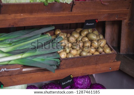 Organic Vegetables in rustic wooden crates displayed at fresh healthy food market counter under the name sign at chalk sign. Red cabbage, cabbage, potatoes, leeks.