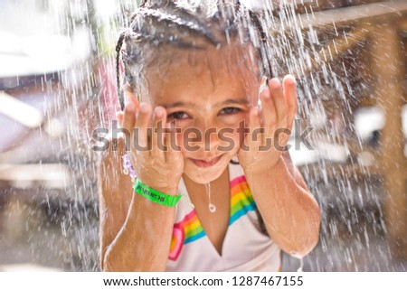 Portrait of a young girl standing under an outdoor shower.