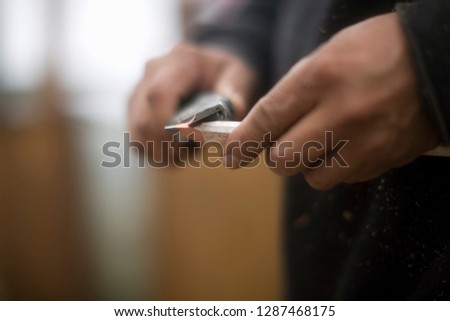 Close-up of a man's hands sharpening a pencil with a knife