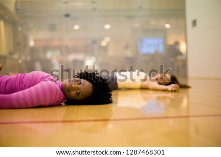 Portrait of a smiling young woman lying on her back on the floor of a studio.