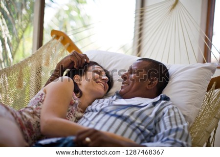 Mid-adult couple cuddling in a hammock.