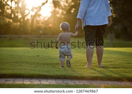 Young toddler holding hands with his father.