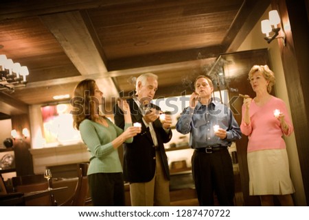 Group smoking cigars and drinking wine