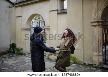 Loving couple having fun outdoors. Man covering eyes of woman with cap.