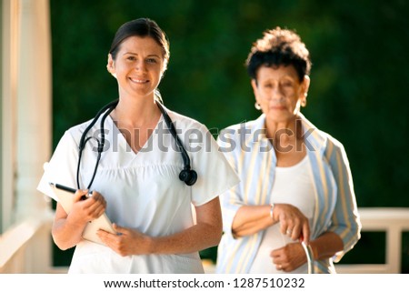Young female nurse standing on the balcony of an elderly patient with nasal tubes.
