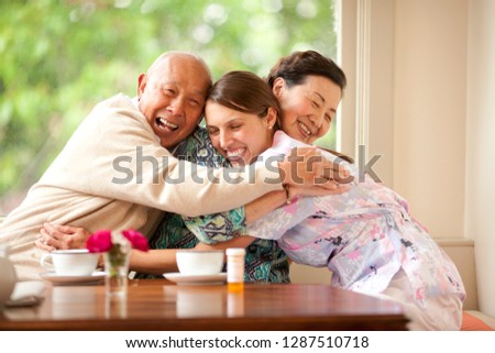 Senior couple hugging their nurse.