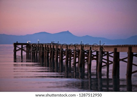 Wooden pier and calm sea at sunset.