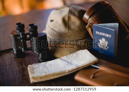 Passport a long with binoculars and a safari hat and notebook.