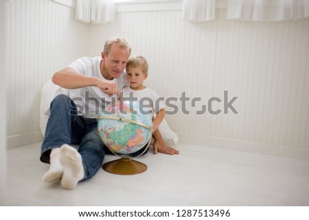 Father looking at a globe of the world with his son.