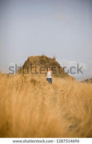 Teenage girl running along a track in a field.