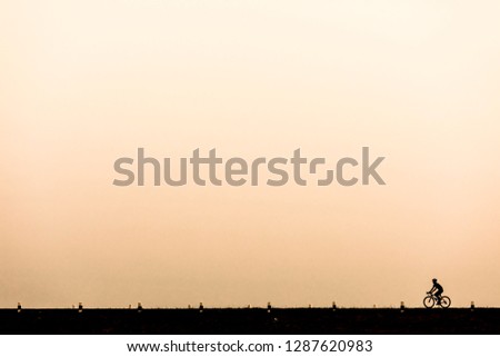 The picture of Silhouette, people riding a bicycle heading forward on the road alone in the evening.