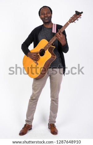 Full body shot of handsome African man playing the guitar