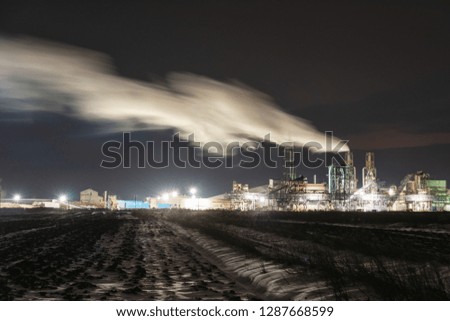 Night riding on a snow-covered field, near an industrial plant.
