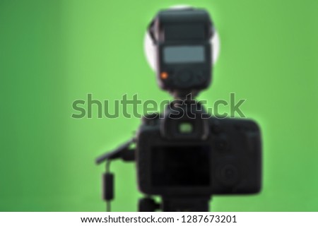 Photographer camera and flash against a green screen background in photography studio. Blurred out of focus background.  No People. Copy space