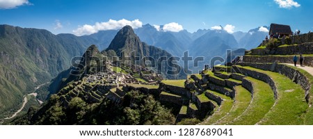 Panoramic view of Machu Picchu ruins in Peru. Behind we can appreciate big and beautiful mountains full of green vegetation. Archaeological site, UNESCO World Heritage Royalty-Free Stock Photo #1287689041