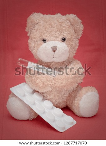 decorations Teddy bear on the red carpet measures temperature with a mercury thermometer and pills