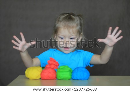 little girl playing with colorful play dough with great interest