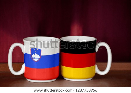 Germany and Slovenia flag on two cups with blurry background