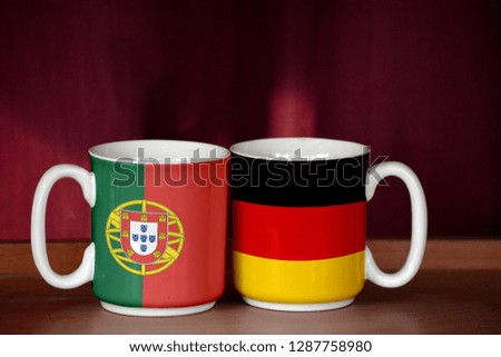 Germany and Portugal flag on two cups with blurry background