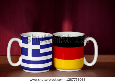 Germany and Greece flag on two cups with blurry background