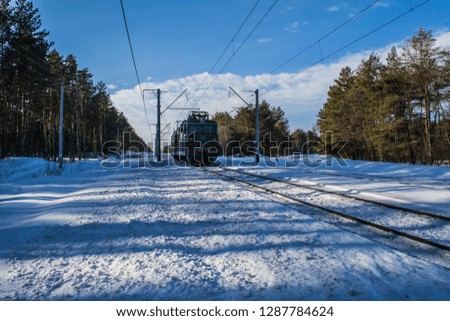 Snowy landscape with railway and a train. Winter forest and blue sky. Beautiful morning in the forest.