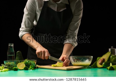 Chef on a black background cuts vegetables for cooking green detox smoothies. Healthy, clean food, weight loss concept, sport,
