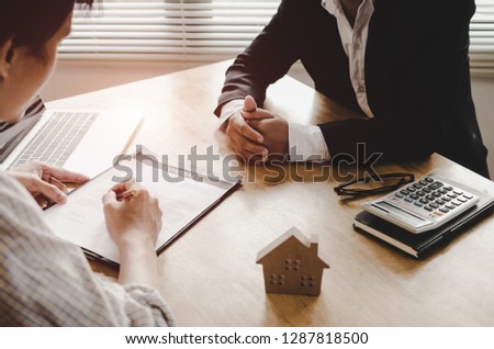 Realtor - young man customer signing contract for buying house with real estate broker in suit at estate agent office, investment, home loan contract, buying house, real estate and insurance concept