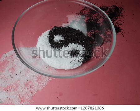 Black and white sand in plate. Abstraction of Yin-Yang, good and evil. Green background.