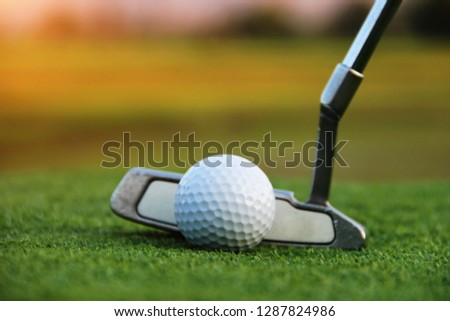Blurred golf ball and golf club in beautiful golf course at sunset background. Close up of golf equipment on green