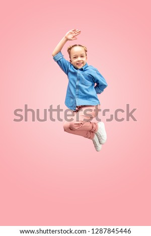 Young happy caucasian teen girl jumping in the air, isolated on pink studio background. Beautiful female full length portrait. Human emotions, facial expression concept.