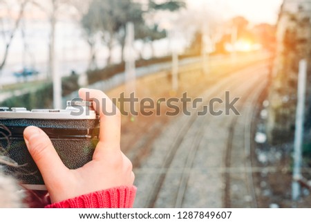 Woman taking a picture with retro camera in front of train tracks at sunset. Historical Istanbul Sirkeci railway track. 