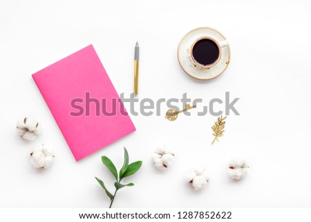 Feminine desk. Notebook and stationery near pink flowers and coffee on white background top view