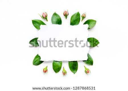Template for greeting card. Mockup with flowers, leaves, white paper on white background top view copy space frame