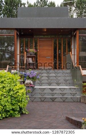 Vertical photo of tiled stairs bordered with hedge shrubs leads to the front door of a home