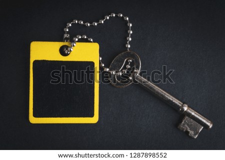 Key and wooden tag on black background with selective focus and crop fragment. Business and motivation concept