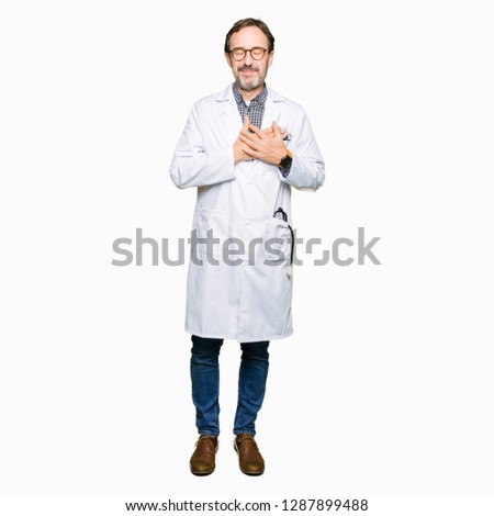 Middle age doctor men wearing medical coat smiling with hands on chest with closed eyes and grateful gesture on face. Health concept.