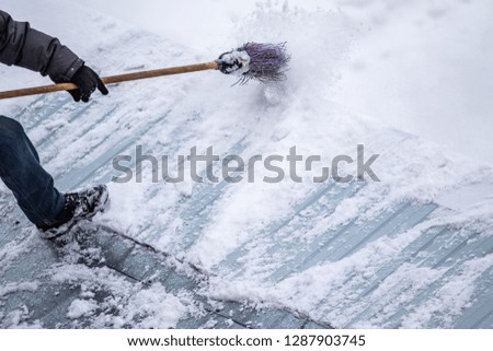 man sweeps the snow with a broom