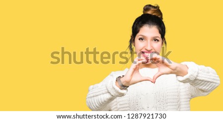 Young beautiful woman wearing winter sweater smiling in love showing heart symbol and shape with hands. Romantic concept.