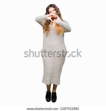 Young beautiful woman wearing winter dress smiling in love showing heart symbol and shape with hands. Romantic concept.