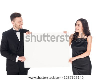 attractive couple in black elegant clothes holding empty board, isolated on white