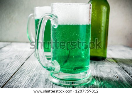 St. Patrick's day concept, two glasses and bottle with cold fresh cold green beer on wooden table, bar counter Background for St. Patrick's day and Oktoberfest menu. Copy space