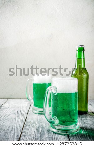 St. Patrick's day concept, two glasses and bottle with cold fresh cold green beer on wooden table, bar counter Background for St. Patrick's day and Oktoberfest menu. Copy space