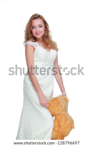 Beautiful bride in a white dress holding a stuffed toy on white background