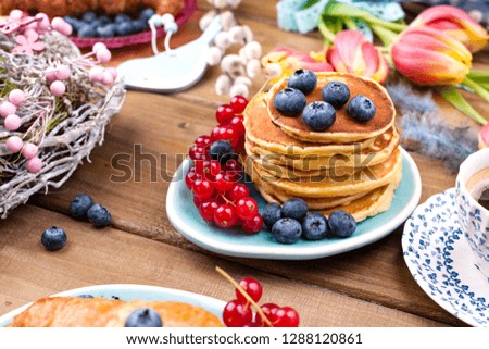 Homemade pastry croissant for breakfast with blueberries and currants and coffee, on a wooden background and spring tulips. Free space for text