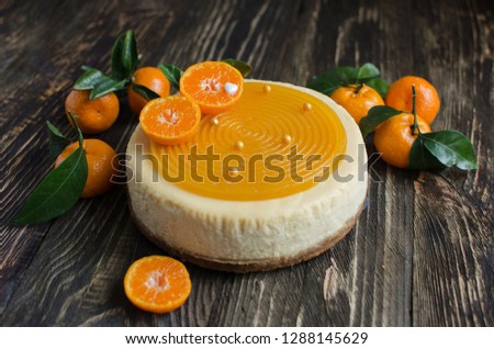 Fruit cheesecake decorated with fresh tangerines on wooden background