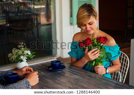 Beautiful loving couple is spending time together in summer ouydoors restaurant February 14 Valentine's Day. Attractive young woman in dress and handsome man romantic. Celebrating Saint Valentine