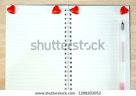 Empty white notebook with cute pen and mini red hearts on the table. Sweet image. Copy space for any text design. Can be use for memo, to do list, event.