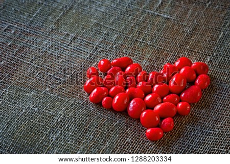 Red sweet candy love heart on gray sackcloth valentines day background. Love romantic valentines day concept with red candy heart on grey background. Love red candy heart background for valentines day