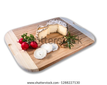 Cheese from France named Tommette des Alpes and white round goat cheese with nuts and radish and parsley on the white background with shadow