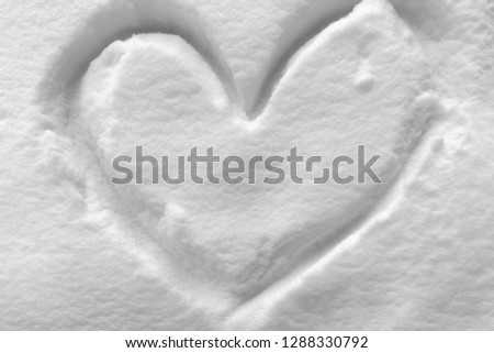 Heart shape symbol drawn on white snow in the cold winter